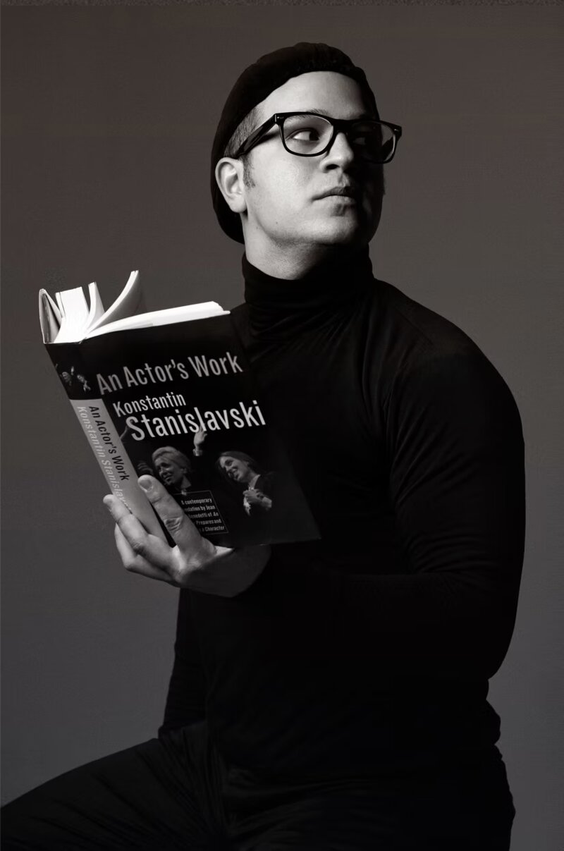 Douglas Widick in character, holding a copy of An Actor's Work
